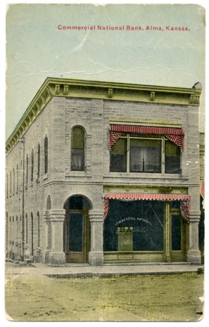 This is a colorized photo postcard showing the Commercial National Bank in Alma, Kansas. This building, a former saloon, was purchased by Louis Palenske in 1907 and the façade was extensively remodeled to accommodate the new bank.