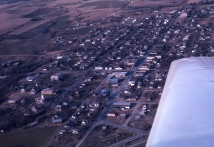 Charles Herman photographed several Wabaunsee County towns from the air in the 1960s. In this view of Alma, one can notice several differences from today. At the bottom of the photo, notice that Flint Hills Foods/Hormel had yet to be constructed. At the top left of the image notice that there was neither a city shop nor a water town on the hilltop. Notice that the Co-op grain elevators and the Hafenstine Construction building had yet to be built. The residential subdivision in the 400 block of West 8th Street was a field when this view was taken.